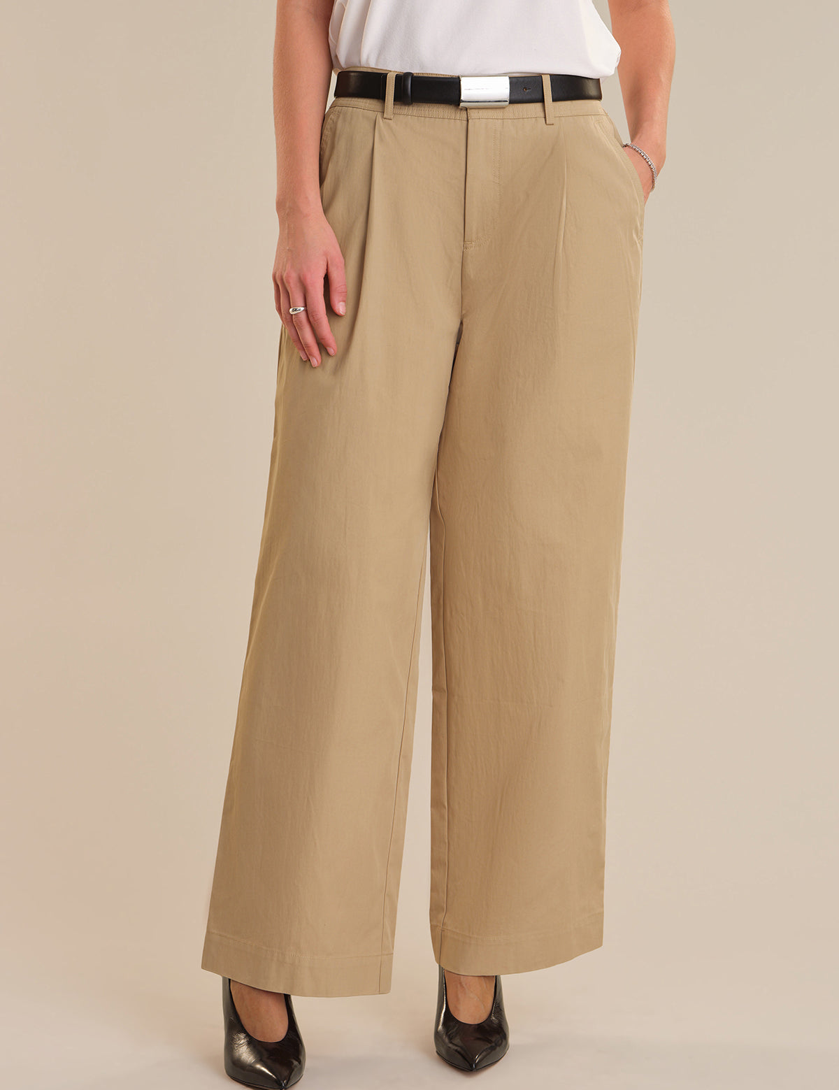 Person wearing beige wide-leg pants on a plain background