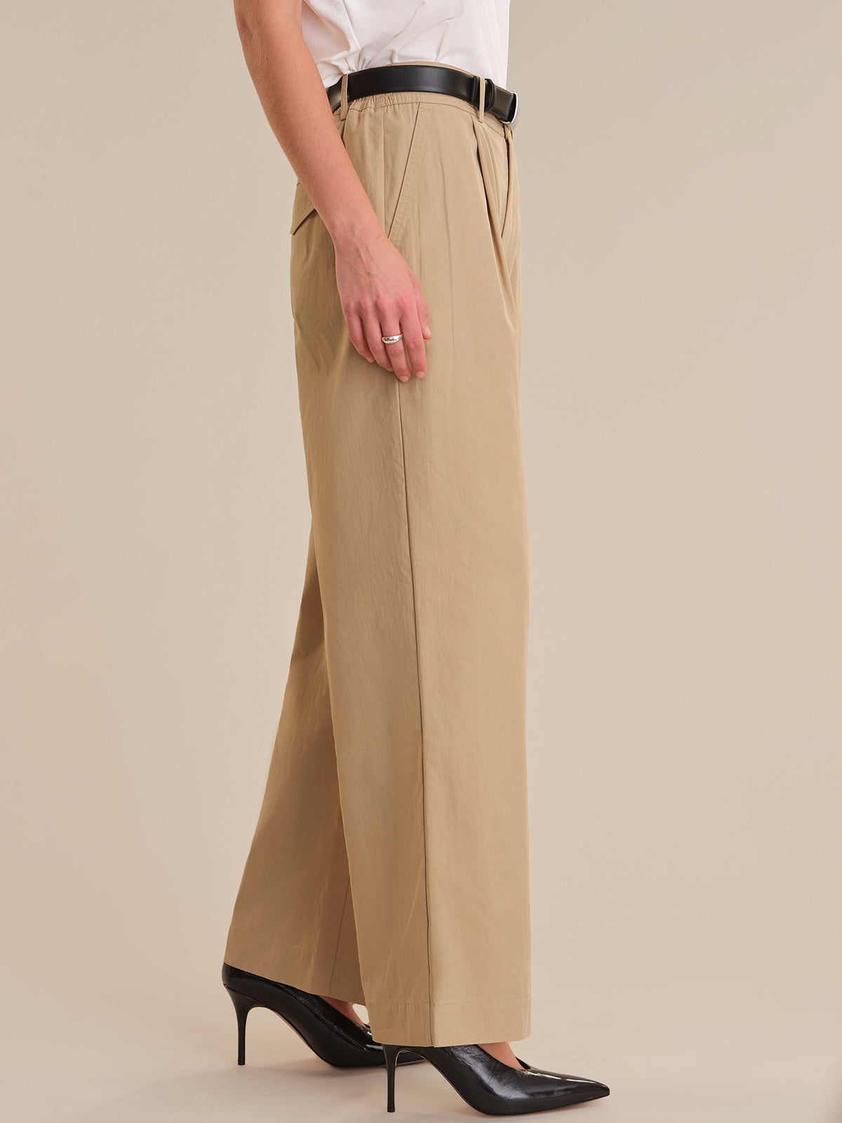 Person wearing beige wide-leg pants with a plain background