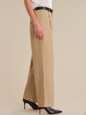 Person wearing beige wide-leg pants with a plain background