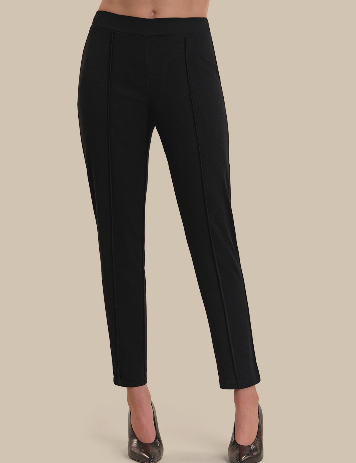 Black pants worn by a person on a beige background