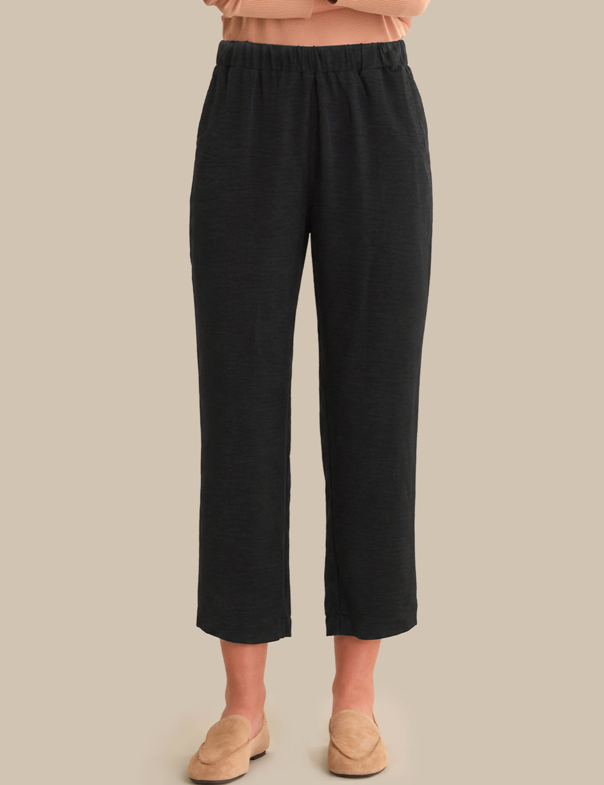 Black pants worn by a person on a beige background
