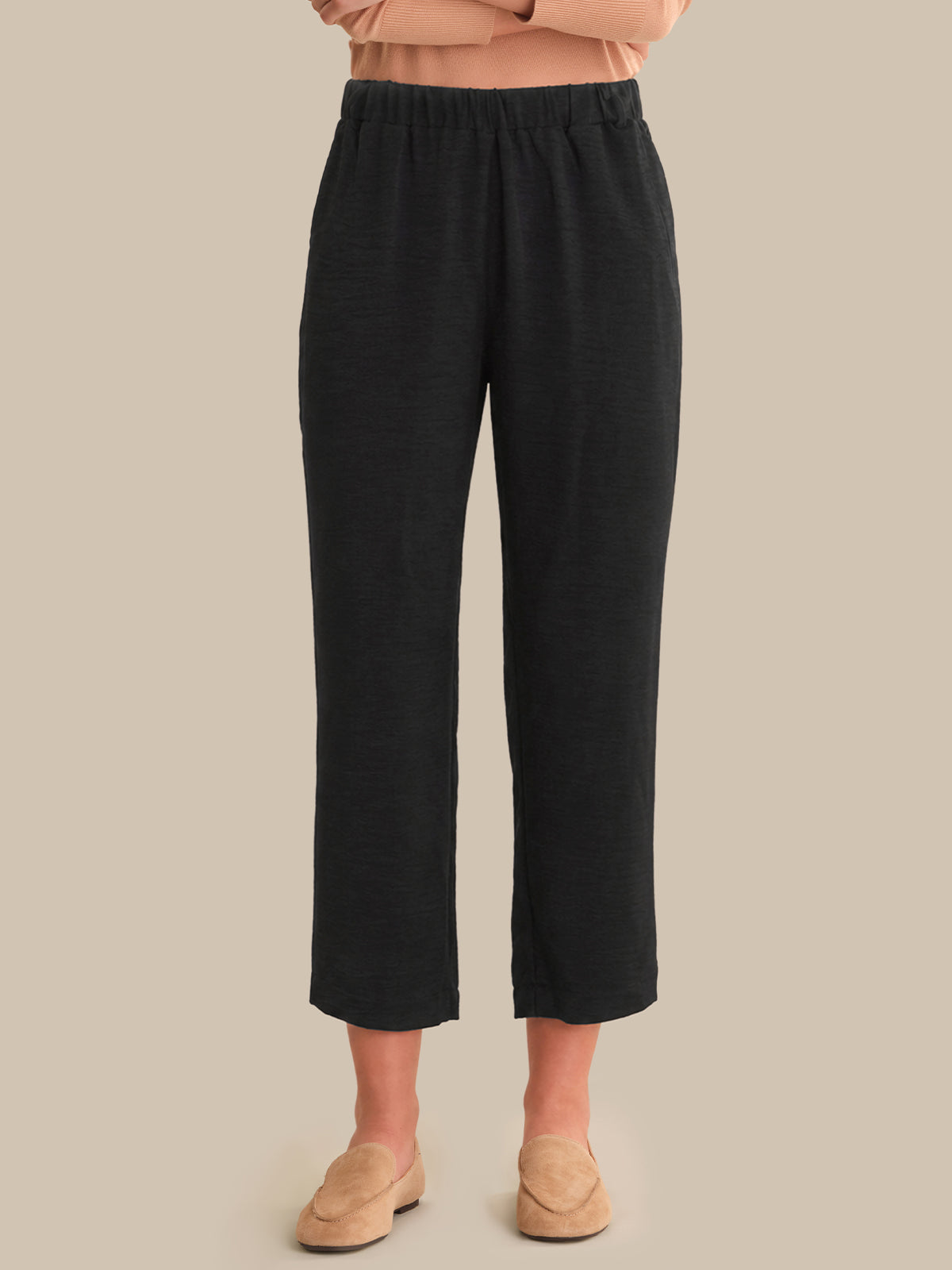 Black pants worn by a person on a beige background