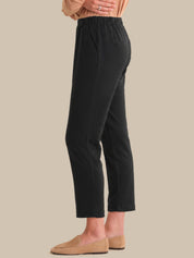 Person wearing black pants and beige shoes on a beige background