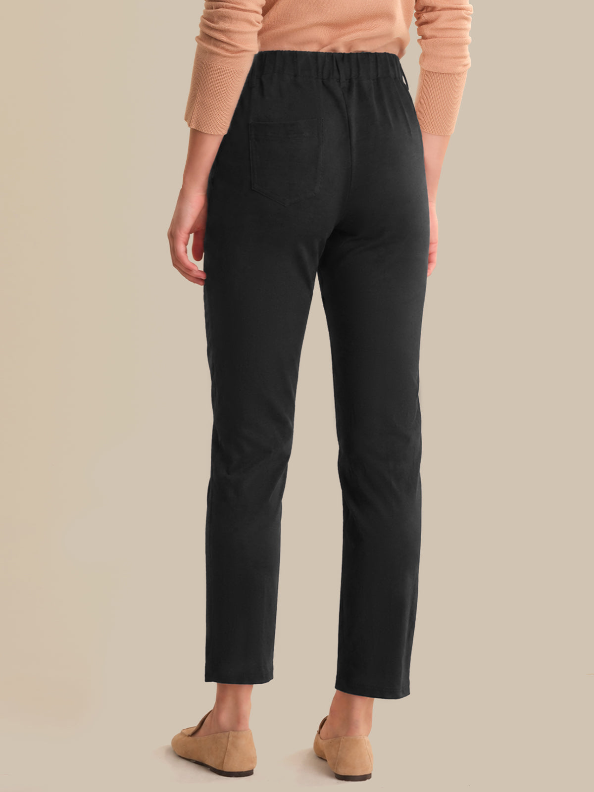 Person wearing black pants and tan shoes on a beige background