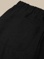 Close-up of black pants with a pocket on a beige background