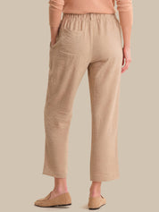 Person wearing beige pants and a matching top on a plain background