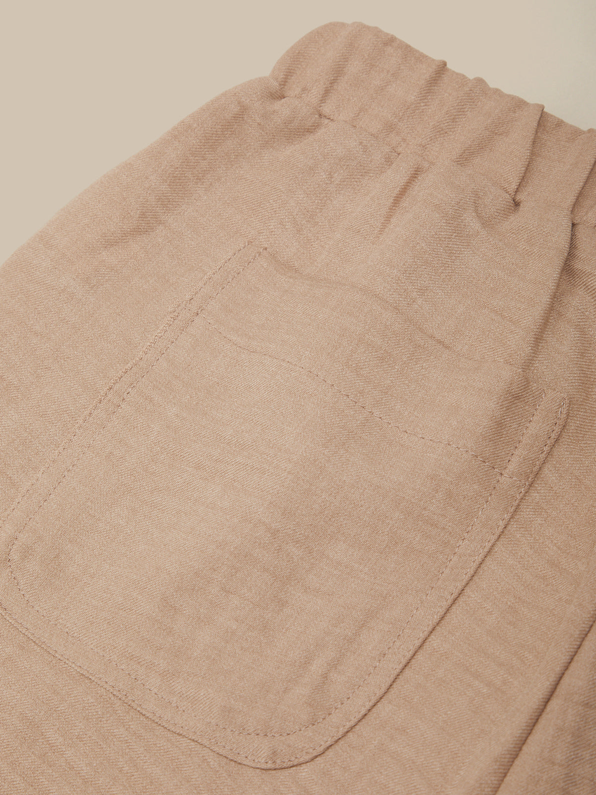 Close-up of beige pants with a pocket on a beige background