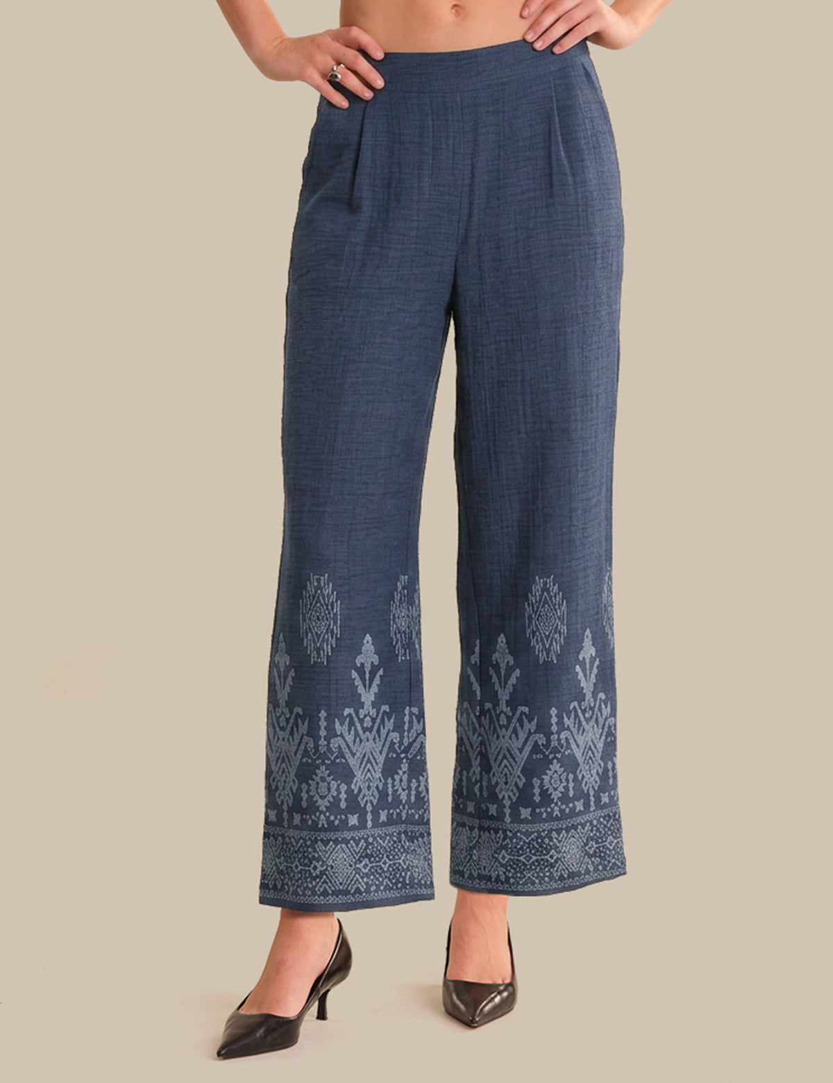 Blue embroidered pants worn by a person on a beige background