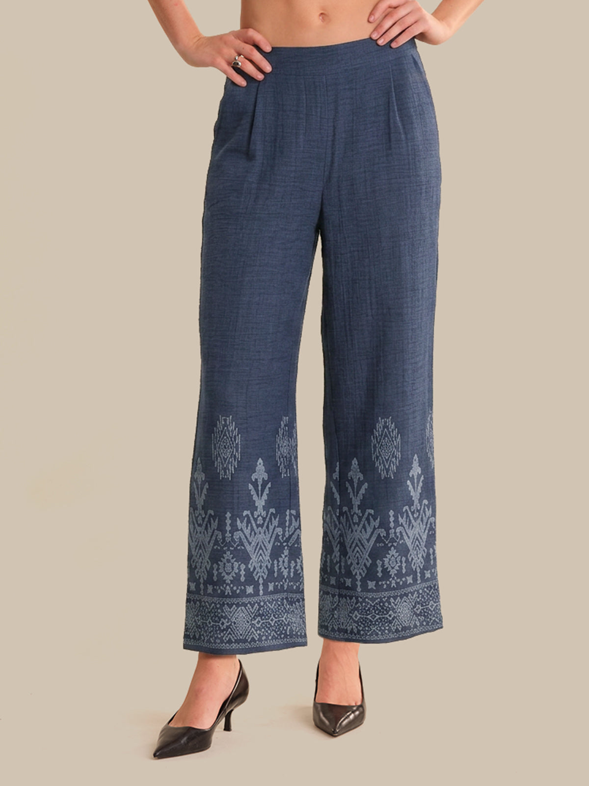Blue embroidered pants worn by a person on a beige background