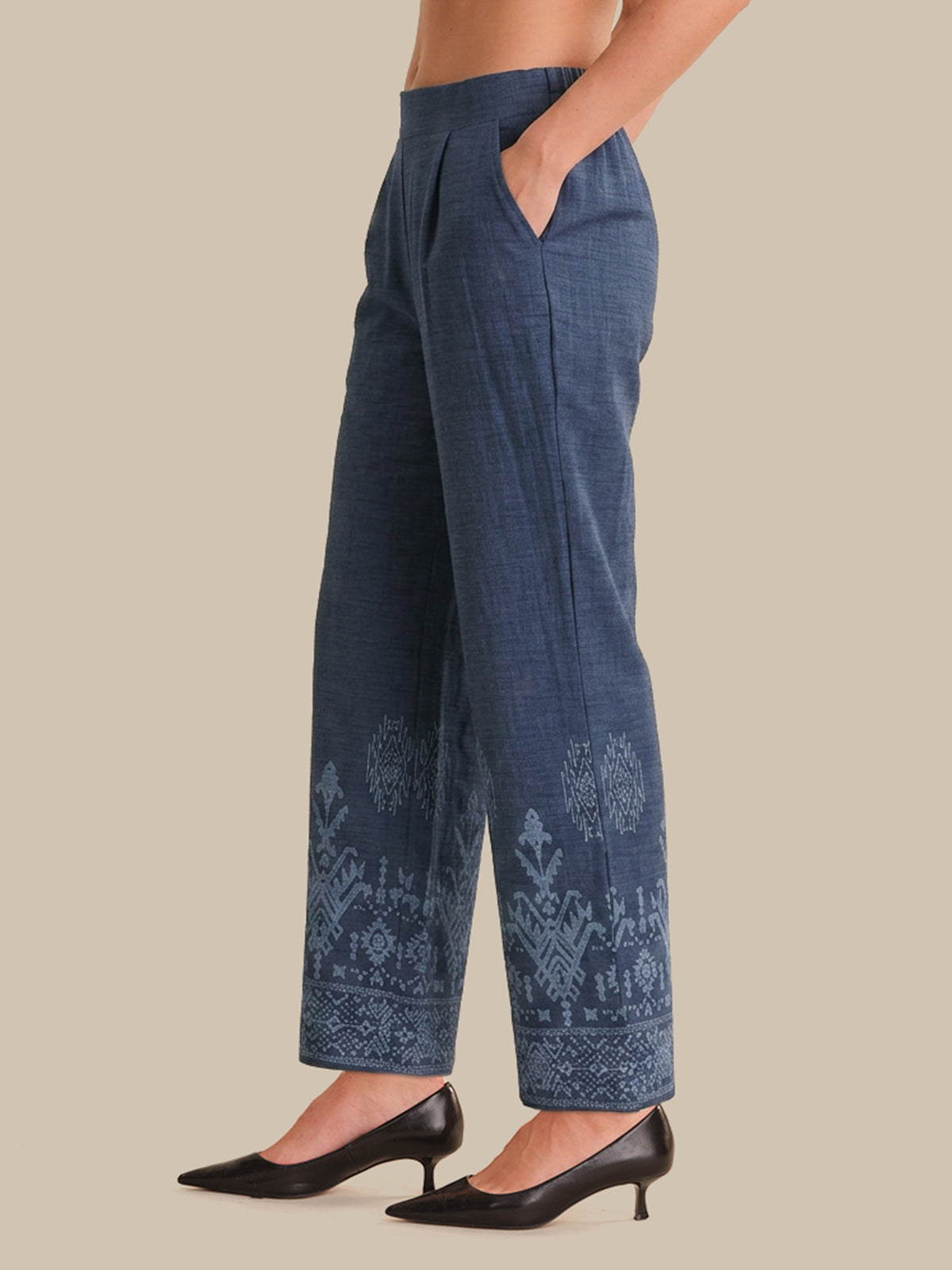Blue embroidered pants worn by a person on a beige background