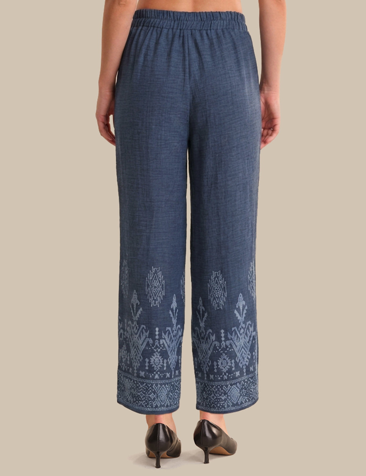 Blue embroidered pants worn by a person on a beige background