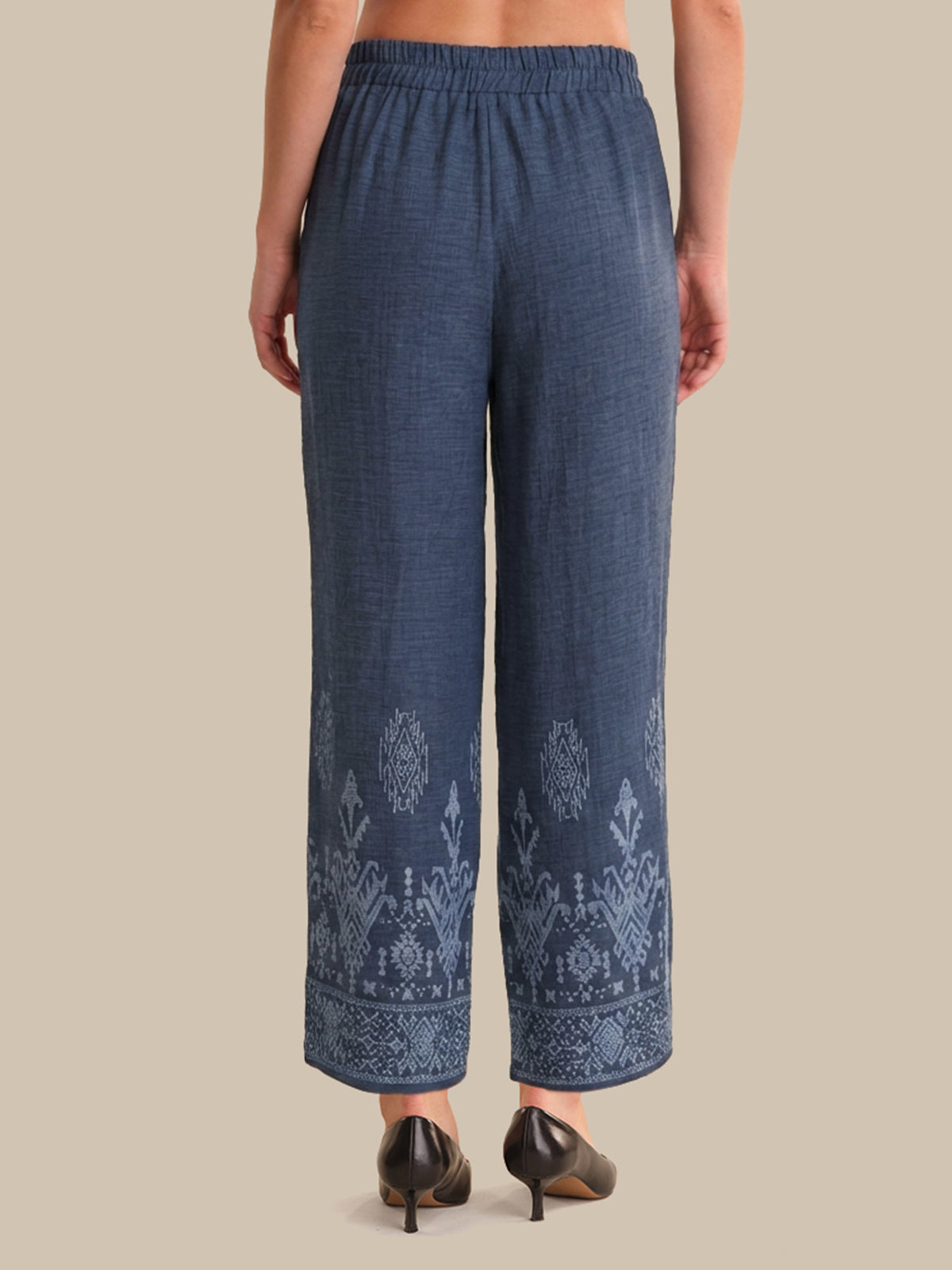Blue embroidered pants worn by a person on a beige background