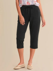 Person wearing black capri pants on a beige background