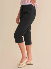 Person wearing black capri pants on a beige background