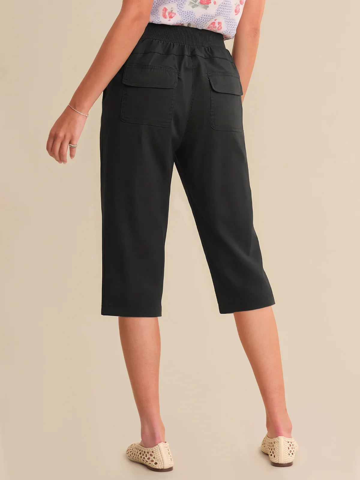 Person wearing black capri pants on a beige background