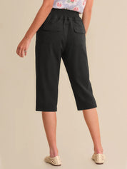 Person wearing black capri pants on a beige background
