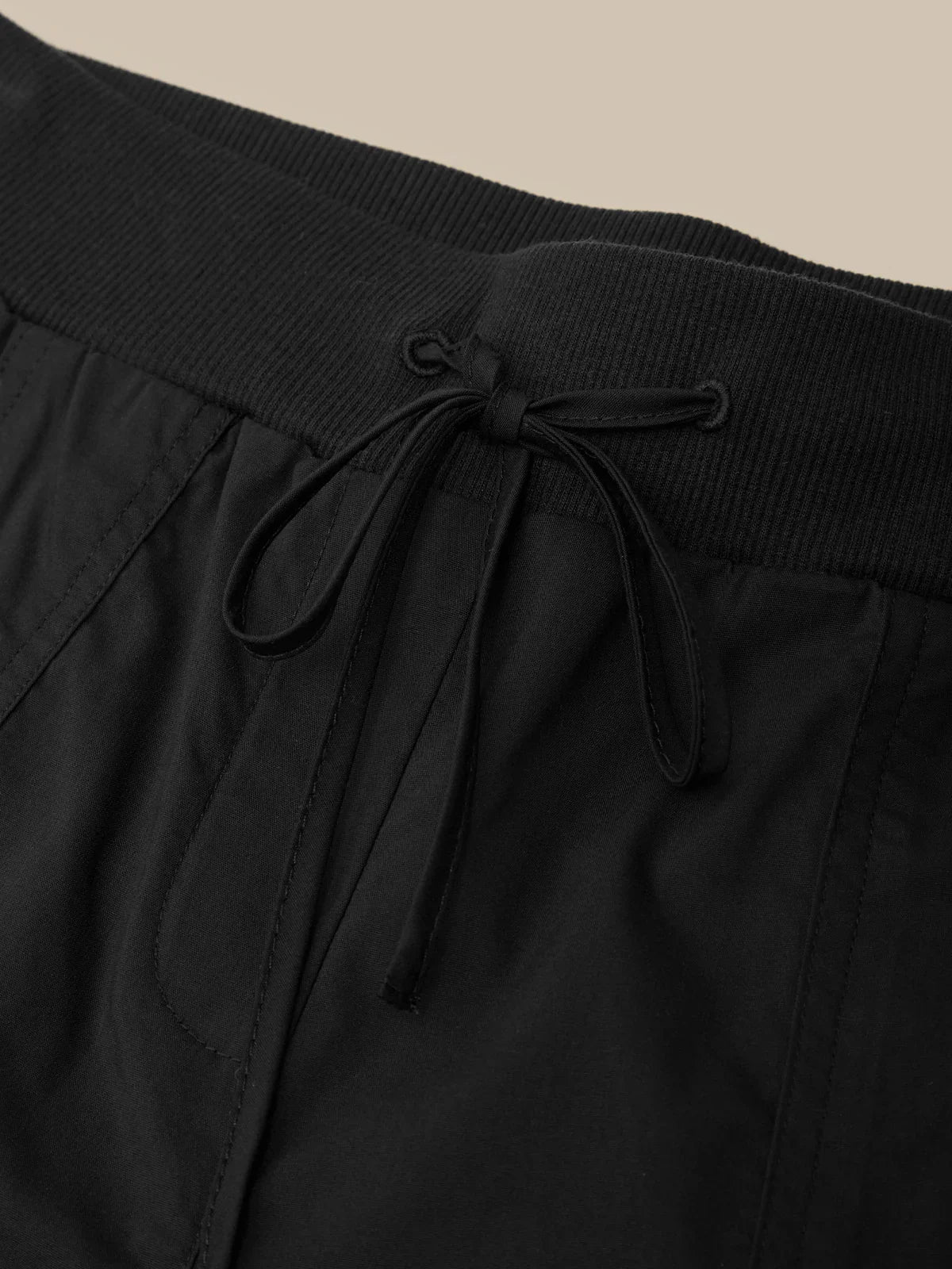 Black pants with a drawstring waist on a beige background