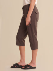 Brown capri pants worn by a person on a beige background