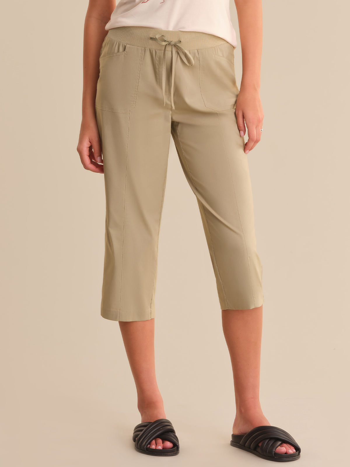 Person wearing beige capri pants on a plain background