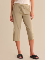 Person wearing beige capri pants on a plain background