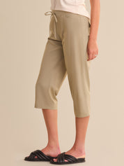 Person wearing beige capri pants on a plain background