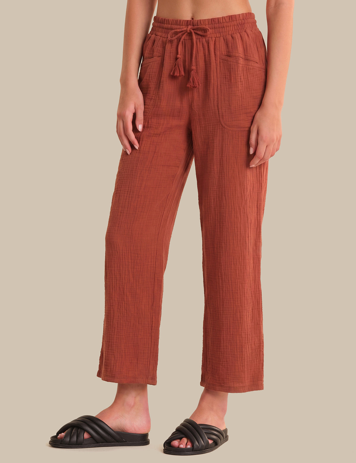 Person wearing rust-colored pants on a beige background