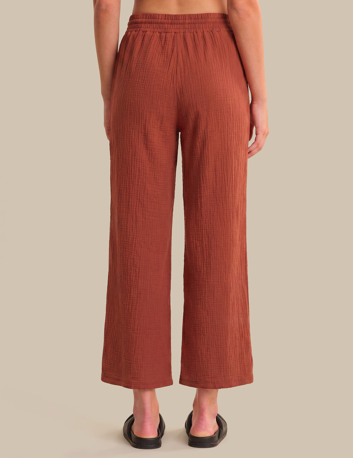 Brown ribbed pants worn by a person on a beige background