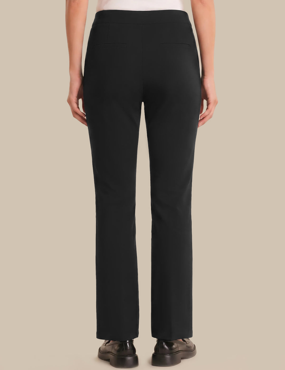 Person wearing black pants on a beige background