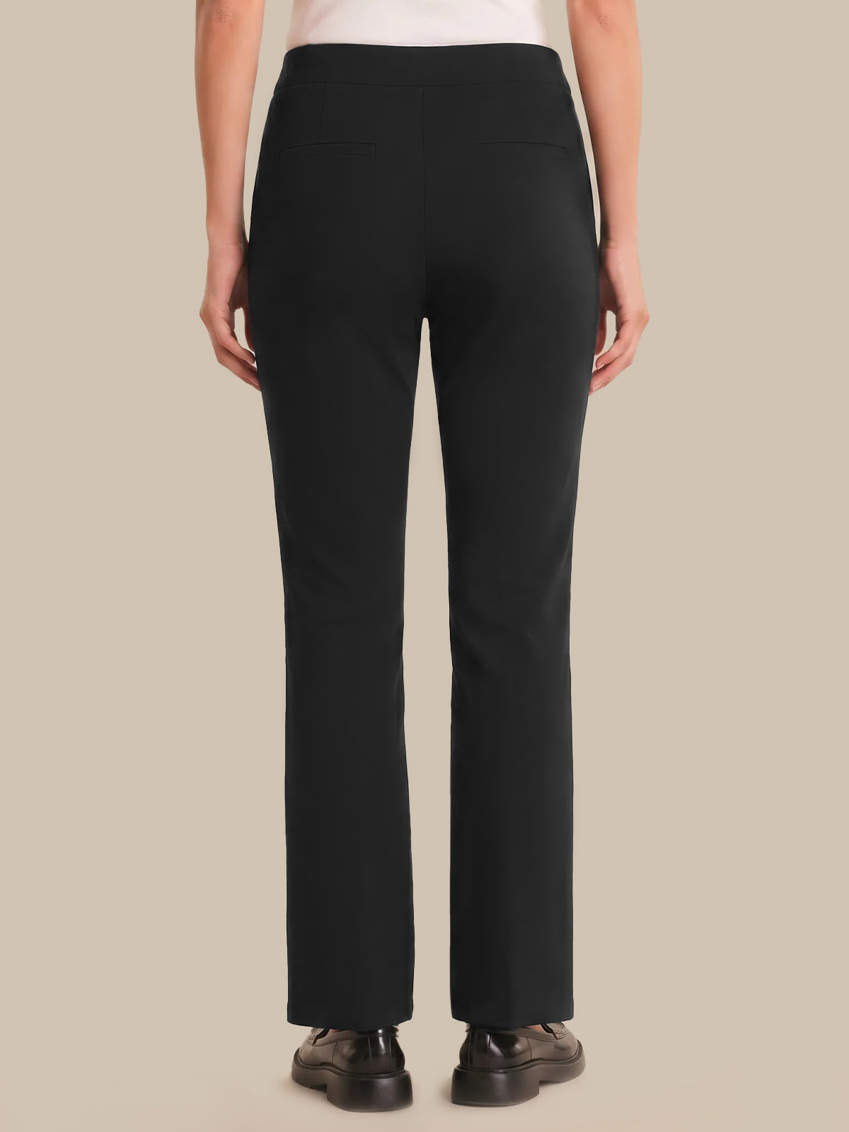 Person wearing black pants on a beige background