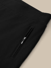 Close-up of a black zippered pocket on a garment against a beige background
