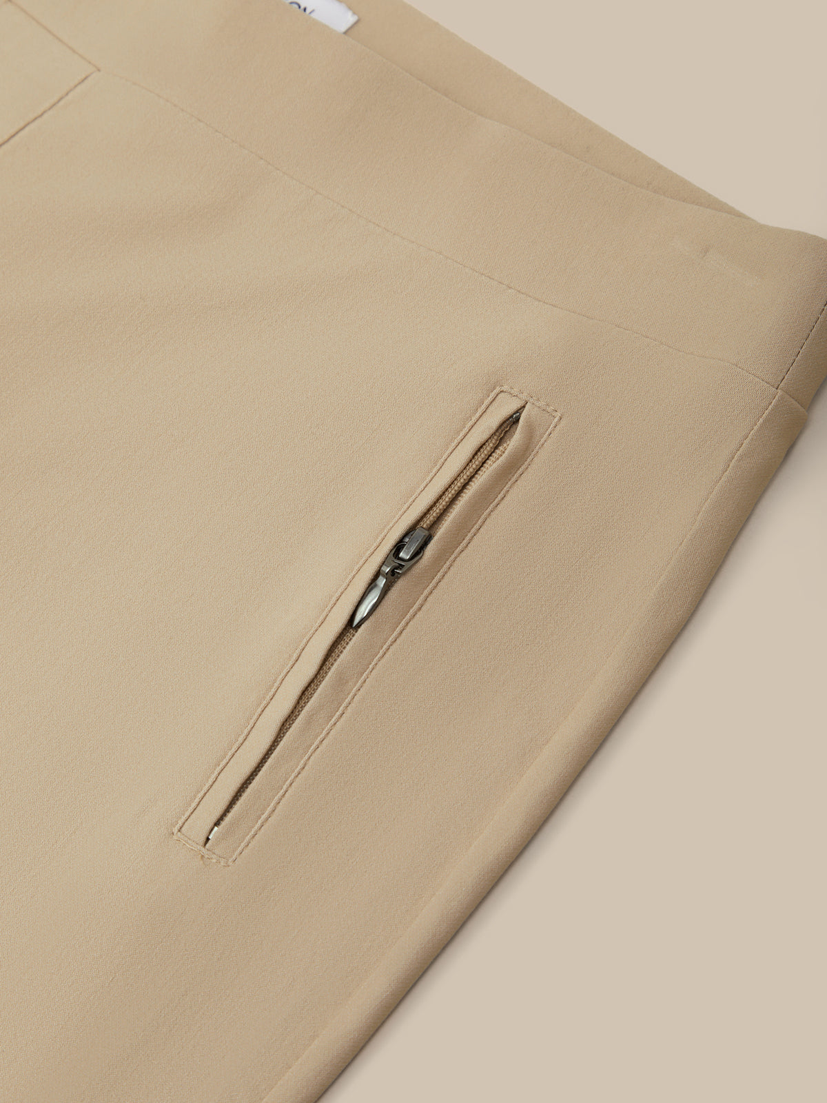 Beige pants with a zipper detail on a beige background