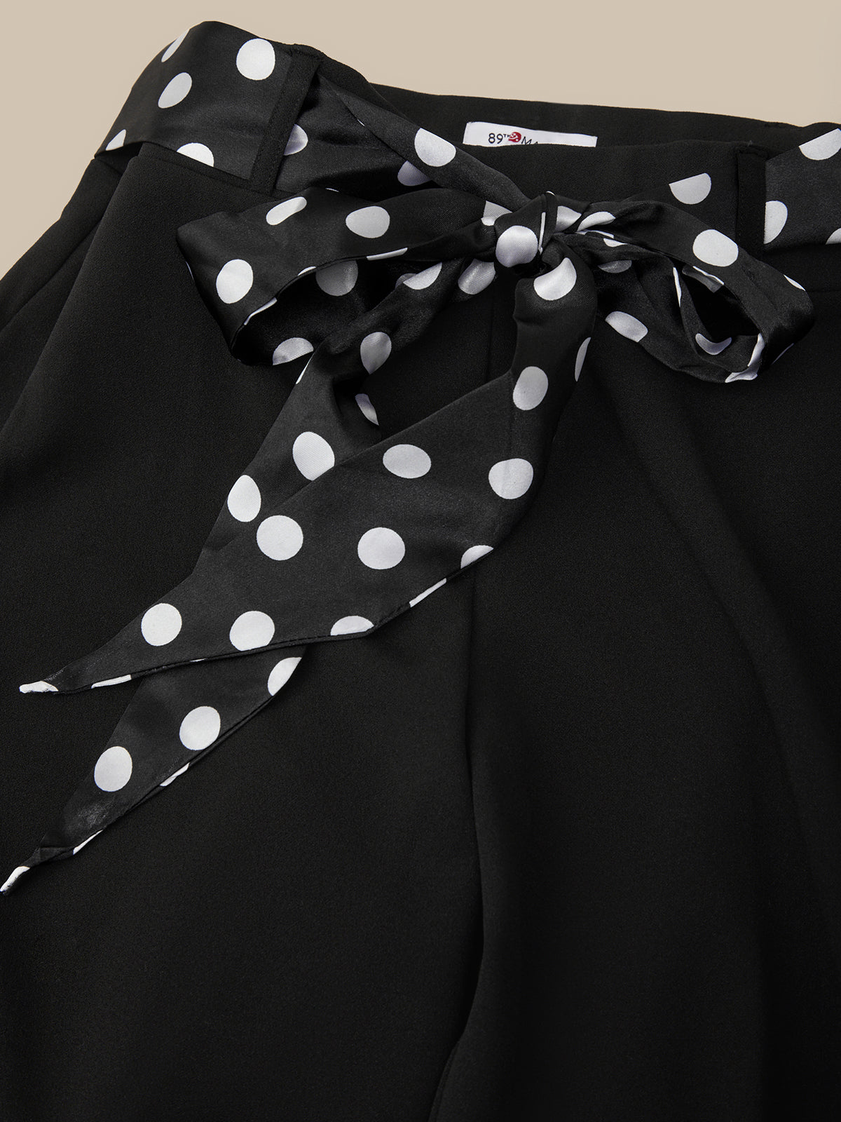 Black top with a polka dot ribbon on a beige background
