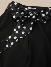 Black top with a polka dot ribbon on a beige background