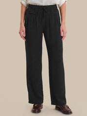 Person wearing black wide-leg pants on a beige background