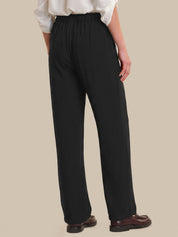 Person wearing black pants and a white shirt on a beige background