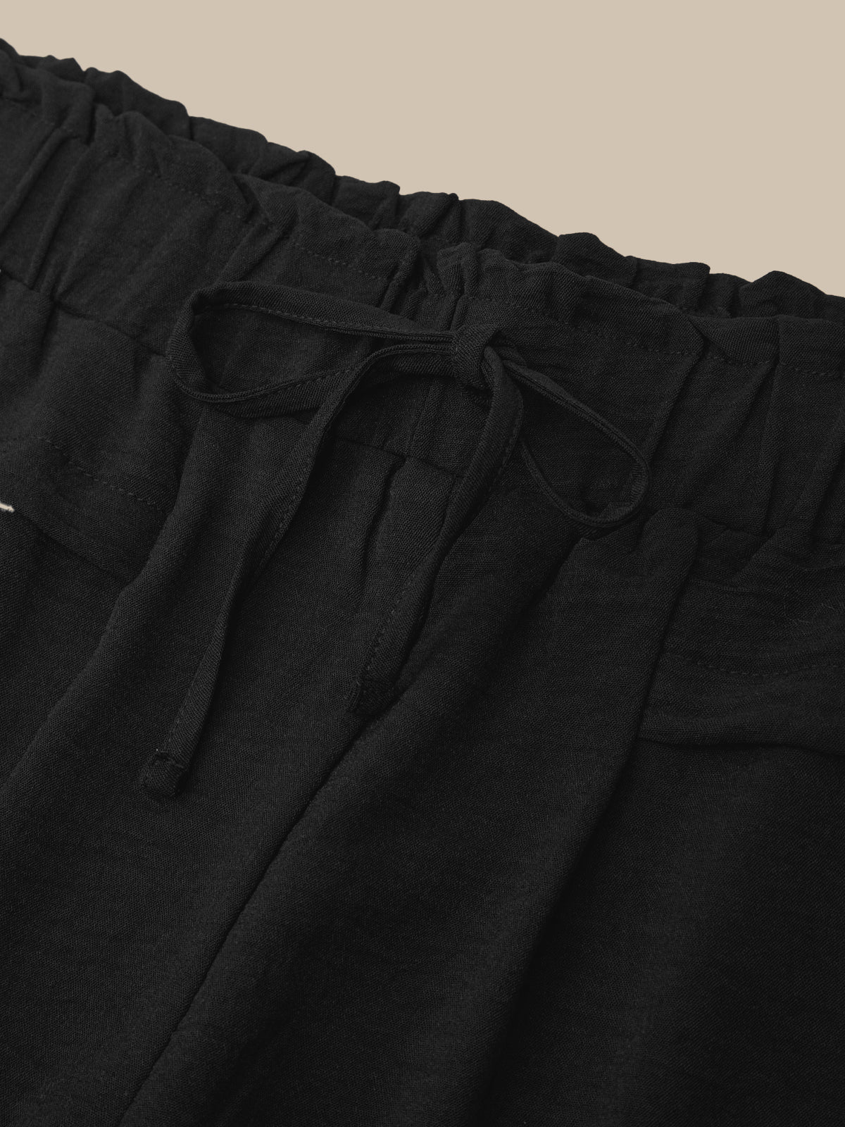 Black pants with drawstring waist on a beige background