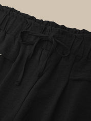 Black pants with drawstring waist on a beige background