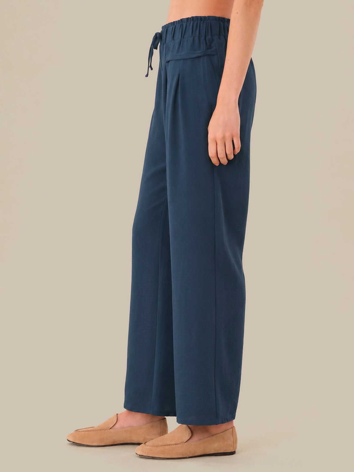 Navy blue wide-leg pants worn by a person on a beige background