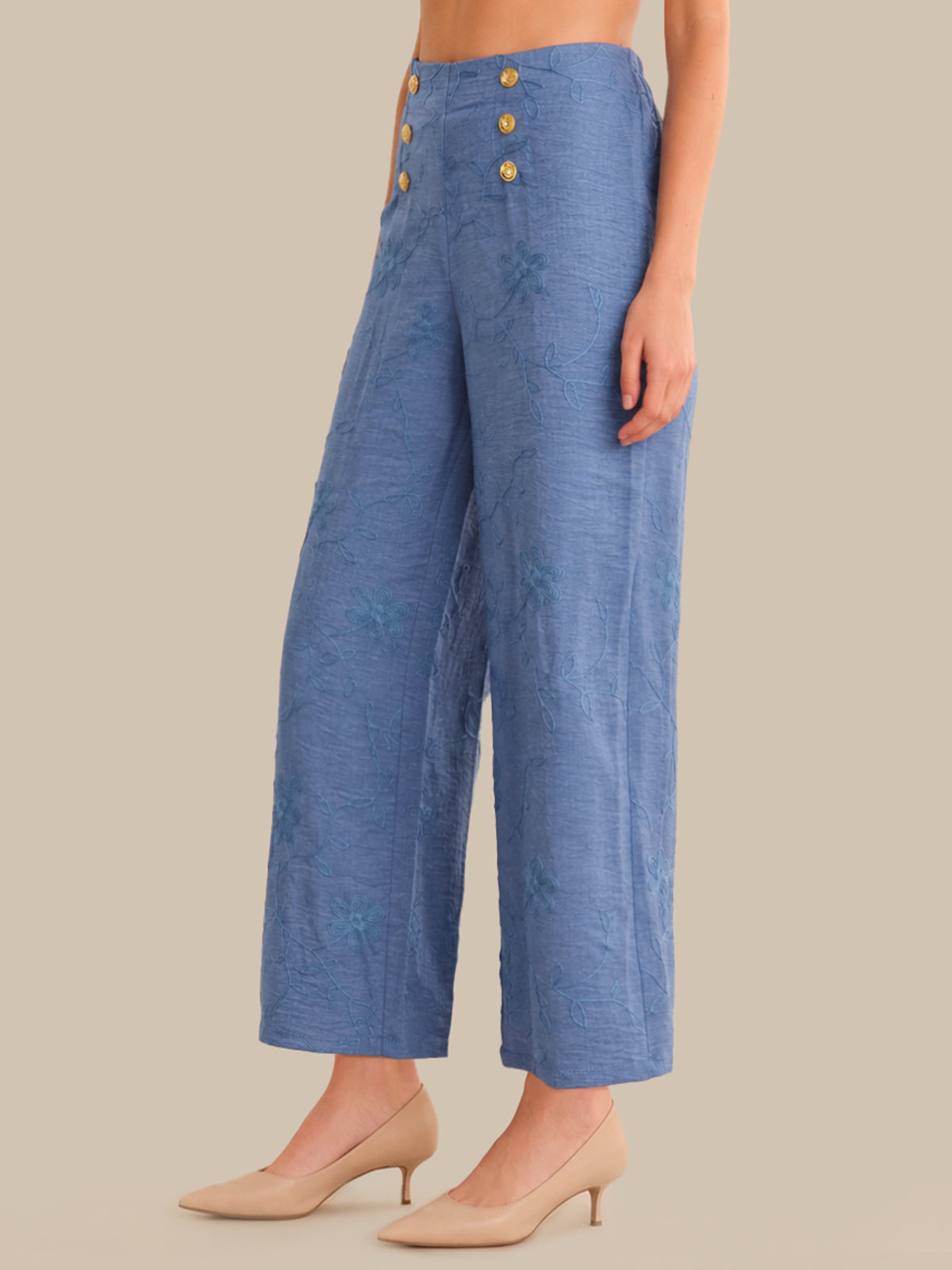 Blue pants with gold buttons worn by a person on a beige background