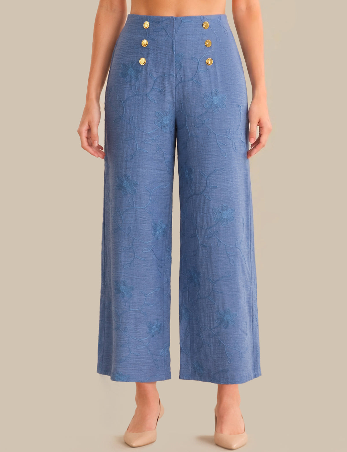 Blue pants with gold buttons worn by a person on a beige background