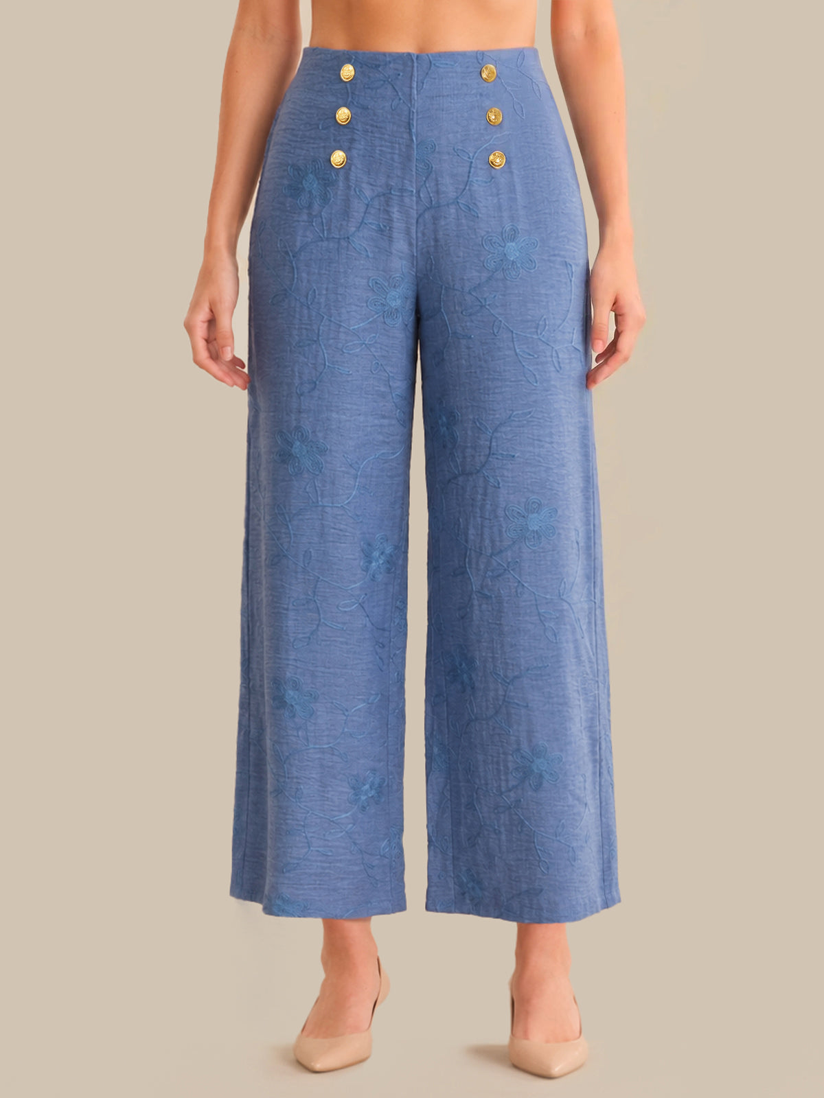 Blue pants with gold buttons worn by a person on a beige background
