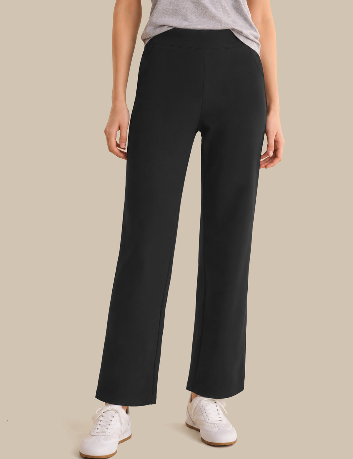 Person wearing black wide-leg pants on a beige background