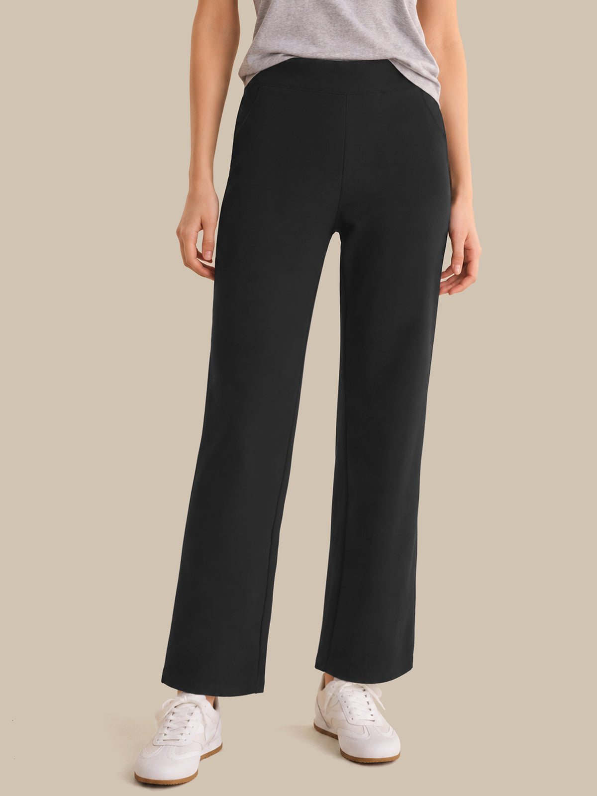 Person wearing black wide-leg pants on a beige background