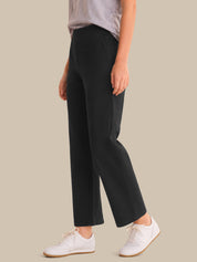 Person wearing black pants and white sneakers on a beige background