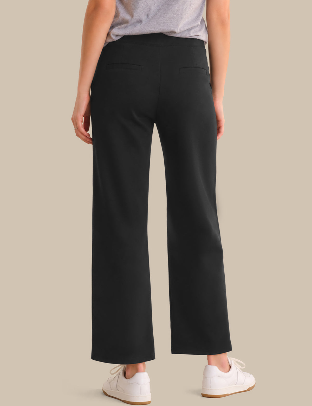 Person wearing black wide-leg pants on a beige background