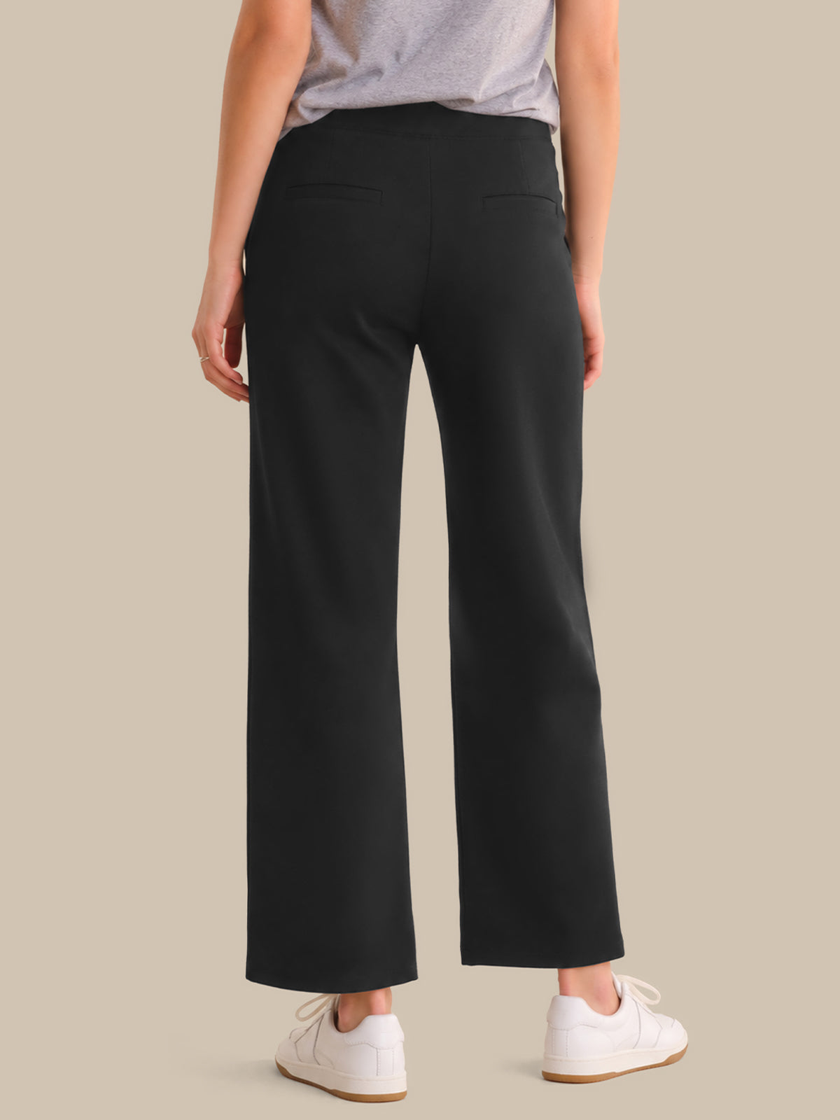Person wearing black wide-leg pants on a beige background