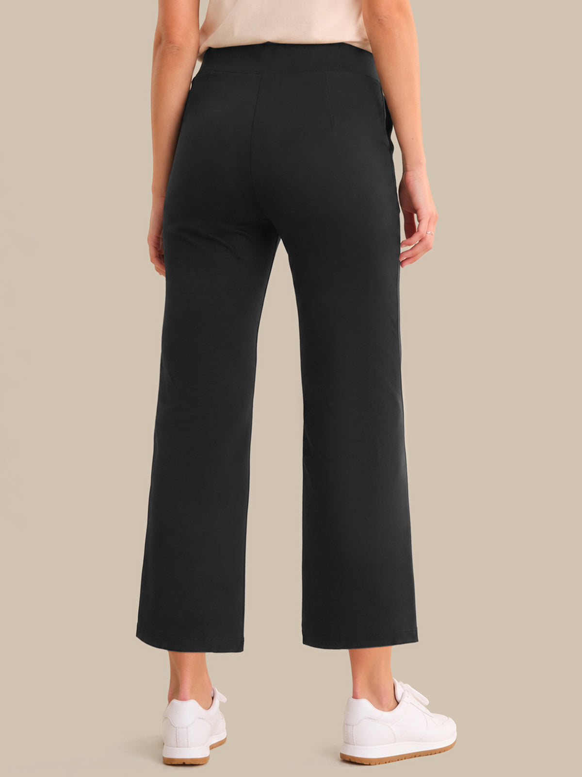 Person wearing black pants on a beige background