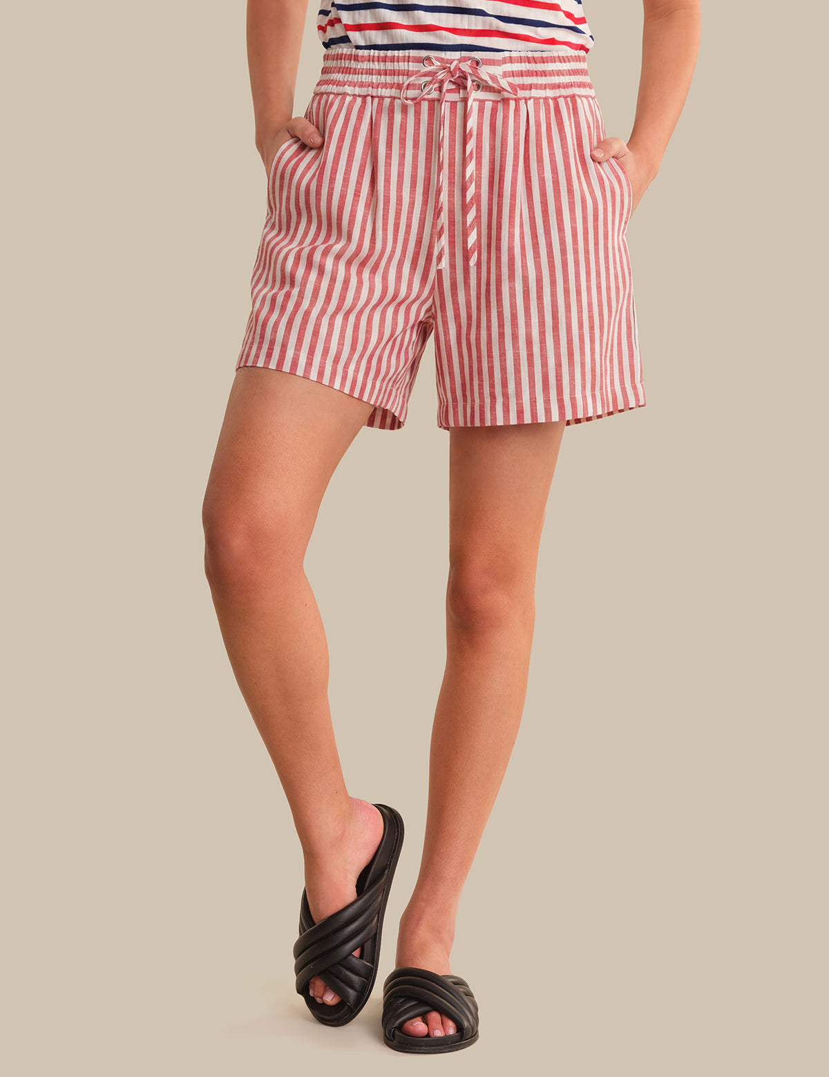 Person wearing red and white striped shorts on a beige background
