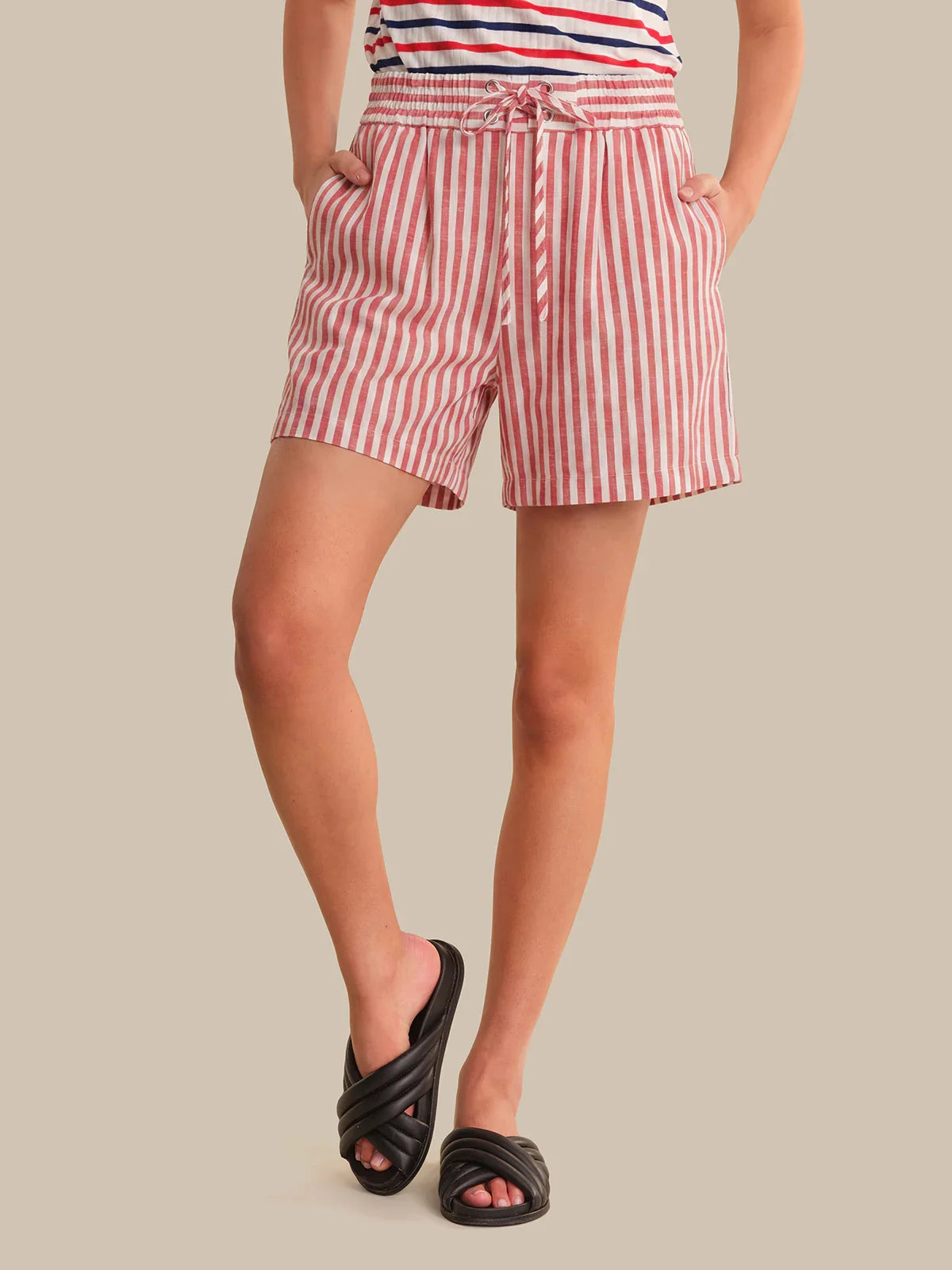 Person wearing red and white striped shorts on a beige background