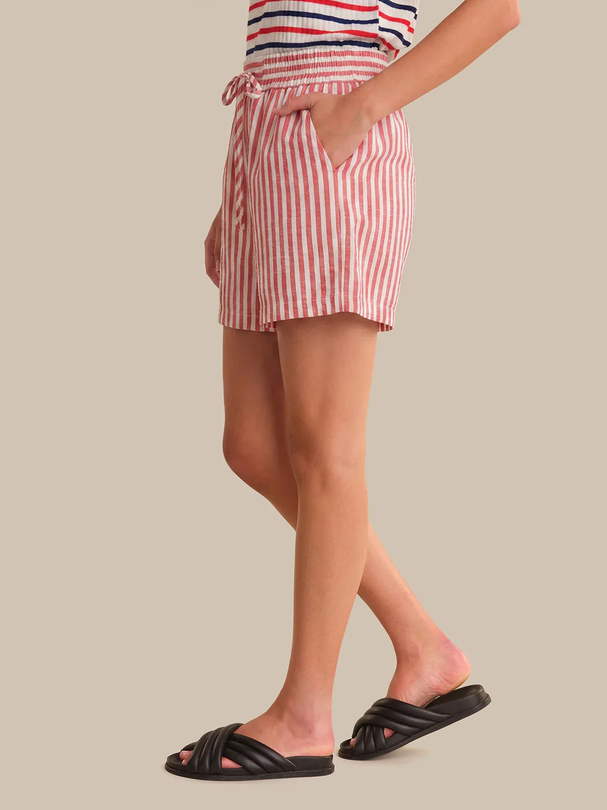 Person wearing red and white striped shorts on a beige background